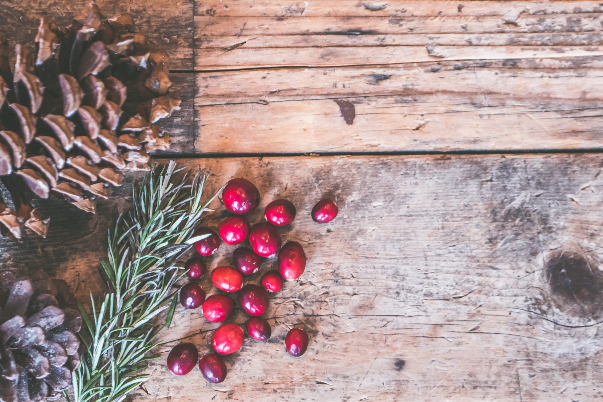 Pine cones and Cranberries sitting on a wood background