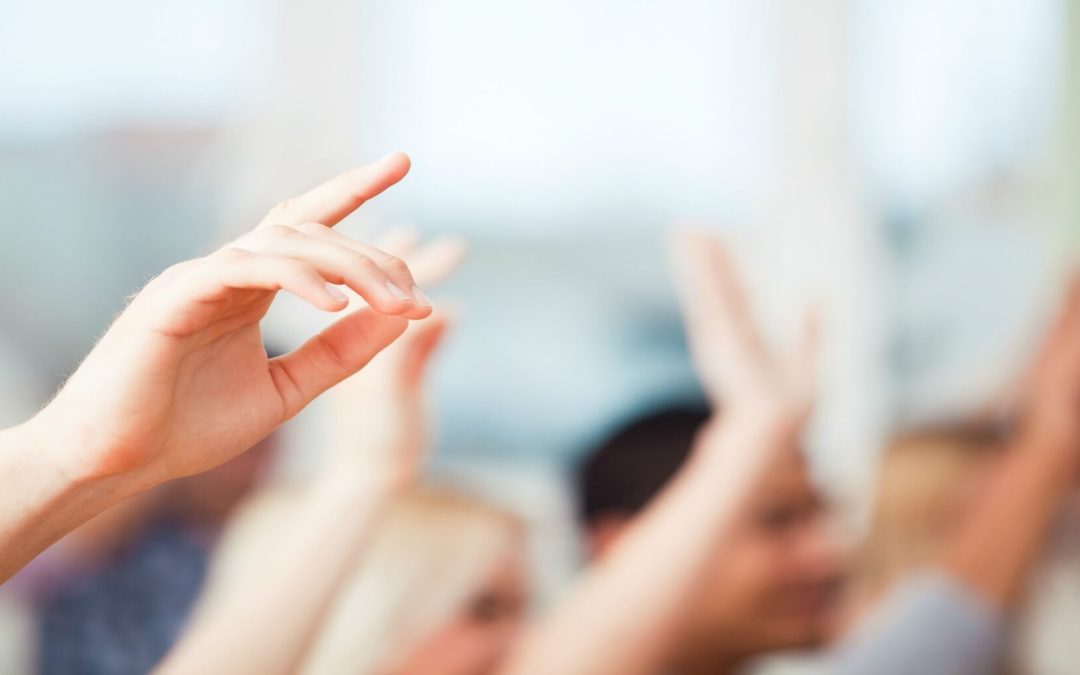 person raising their hand with a blurred background